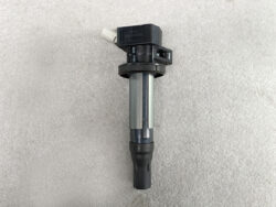 Automotive ignition coil with a rubber boot, placed on a gray concrete surface