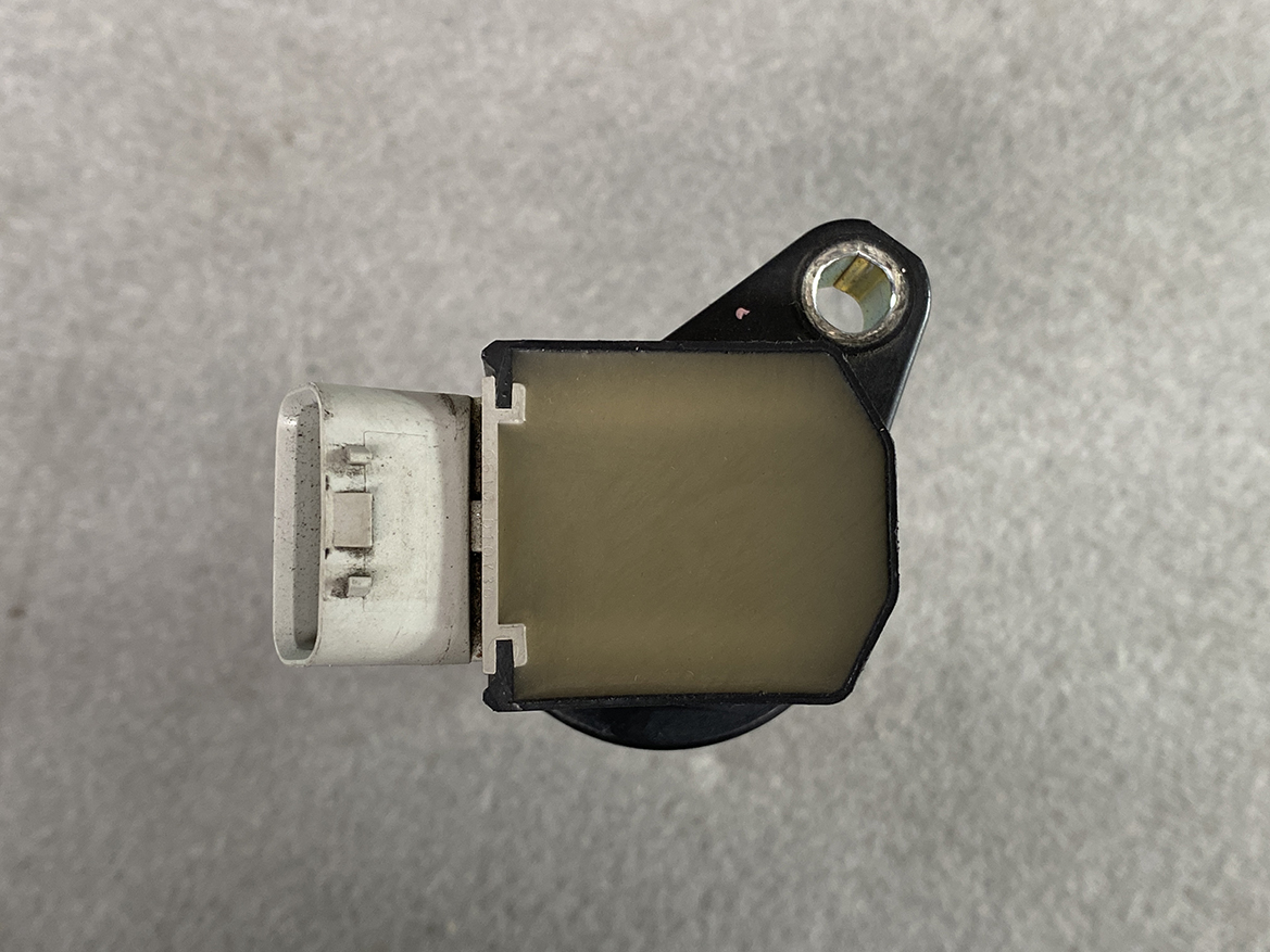 TOY-COIL-B2050_6 TOYOTA / DAIHATSU Genuine IGNITION COIL / 19500-B2050 / KF Engine » NZ.95 » JDM-PARTS NZ » JDM-PARTS NZ Automotive engine sensor with a white electrical connector on the left and a mounting hole on the right side. TOYOTA / DAIHATSU Genuine IGNITION COIL / 19500-B2050 / KF Engine » JDM-PARTS NZ