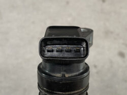 Close-up of a four-pin electrical connector on a black cylindrical sensor.