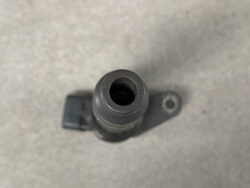 Top-down view of a gray plastic cylindrical connector with a hollow center and a mounting tab with a hole