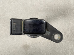 Black automotive sensor with a rectangular electrical connector on the left and a mounting ear with a bolt hole on the right.