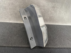 Plastic car tail light housing laid on its side, showing two mounting holes and clear lens sections.