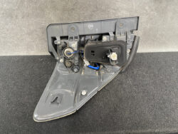 Rear car tail light assembly with the cover removed, showing bulbs, wiring, and connectors inside the gray plastic housing
