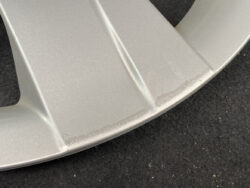 Close-up of a silver-painted metal rim edge with light scuff marks on a dark surface.