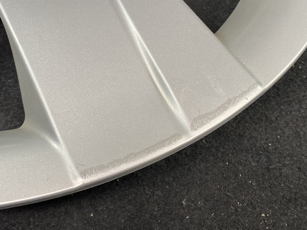 B391_7 TOYOTA RACTIS NSP120, NCP120 Genuine 16inch WHEEL CAP / HUB CAP 42602-52460 » NZ.95 » JDM-PARTS NZ » JDM-PARTS NZ Close-up of a silver-painted metal rim edge with light scuff marks on a dark surface. TOYOTA RACTIS NSP120, NCP120 Genuine 16inch WHEEL CAP / HUB CAP 42602-52460 » JDM-PARTS NZ