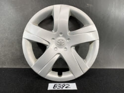 Silver Toyota hubcap with a five-spoke design and center emblem, resting on a dark surface.