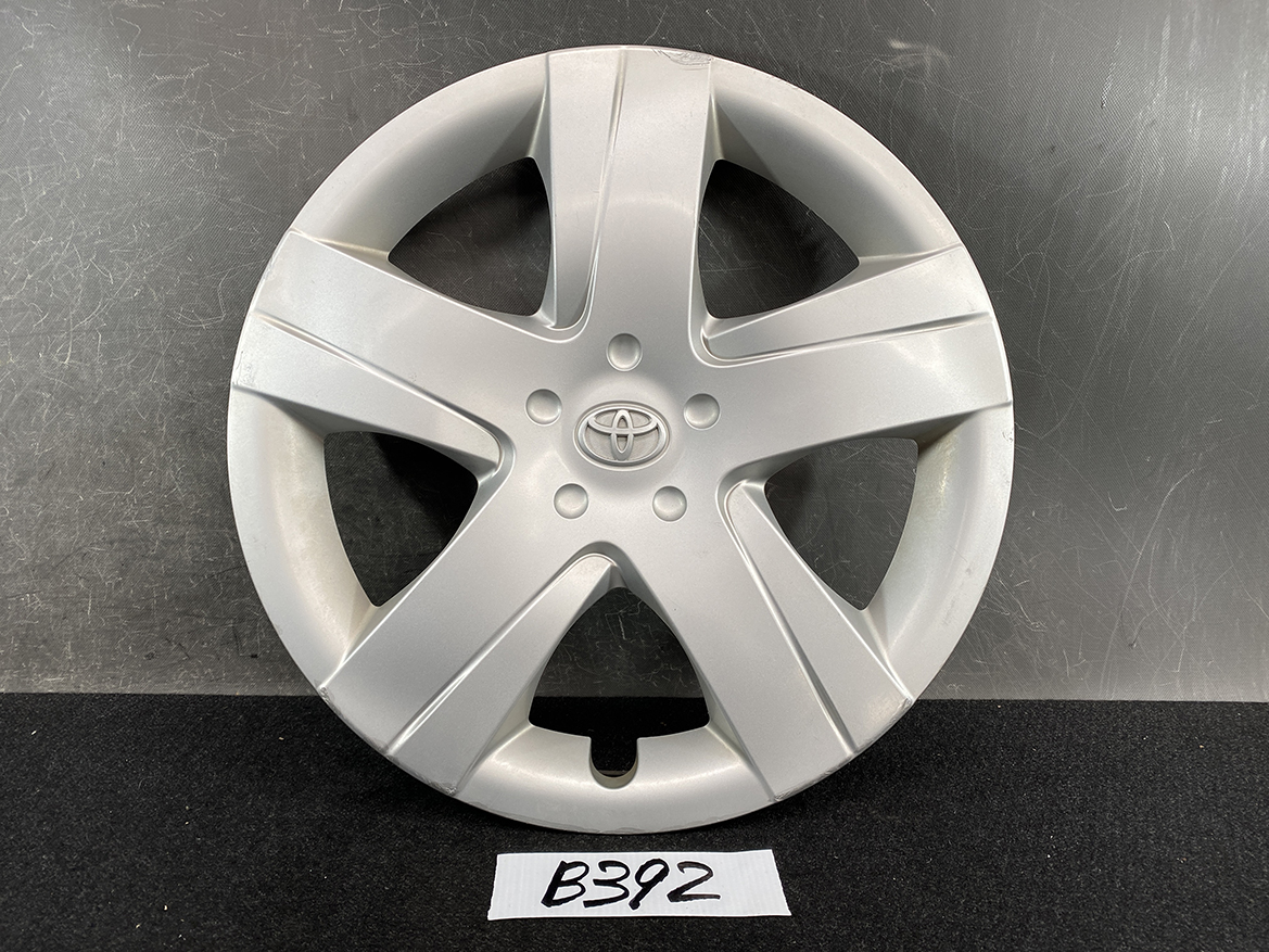 B392_1 TOYOTA RACTIS NSP120, NCP120 Genuine 16inch WHEEL CAP / HUB CAP 42602-52460 » NZ.95 » JDM-PARTS NZ » JDM-PARTS NZ Silver Toyota hubcap with a five-spoke design and center emblem, resting on a dark surface. TOYOTA RACTIS NSP120, NCP120 Genuine 16inch WHEEL CAP / HUB CAP 42602-52460 » JDM-PARTS NZ