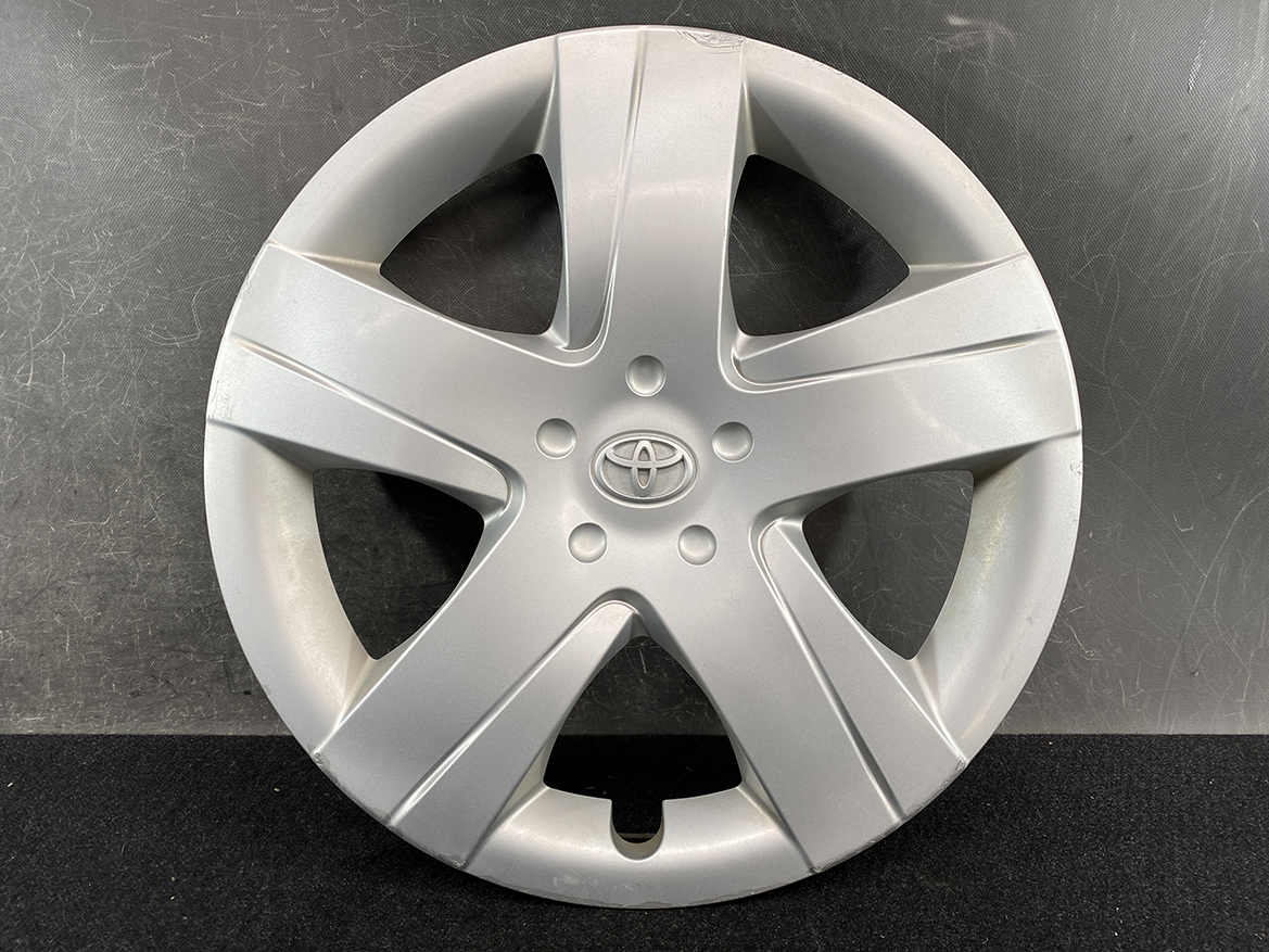 B392_2 TOYOTA RACTIS NSP120, NCP120 Genuine 16inch WHEEL CAP / HUB CAP 42602-52460 » NZ.95 » JDM-PARTS NZ » JDM-PARTS NZ Silver Toyota wheel cover with five spokes and a central logo, resting on a dark background. TOYOTA RACTIS NSP120, NCP120 Genuine 16inch WHEEL CAP / HUB CAP 42602-52460 » JDM-PARTS NZ