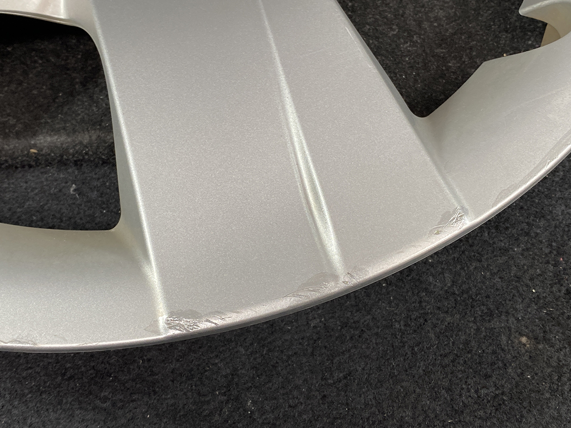 B392_5 TOYOTA RACTIS NSP120, NCP120 Genuine 16inch WHEEL CAP / HUB CAP 42602-52460 » NZ.95 » JDM-PARTS NZ » JDM-PARTS NZ Silver alloy wheel with noticeable scrape marks along the lower lip rim area against a dark background, indicating minor damage. TOYOTA RACTIS NSP120, NCP120 Genuine 16inch WHEEL CAP / HUB CAP 42602-52460 » JDM-PARTS NZ