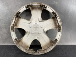 Dusty gray Toyota hubcap with five-spoke design and center Toyota emblem.
