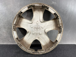 Round beige plastic hubcap with five curved spokes and a central Toyota emblem (dusty).