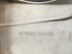 Close-up of a stamped part/serial number 42602-52460 on a dusty beige surface.
