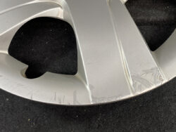 Close-up of a silver alloy car wheel rim with multiple scrapes along the edge.