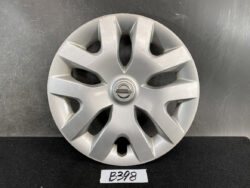 Silver Nissan hubcap with eight curved spokes and central Nissan emblem on a dark surface.