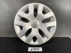 Silver Nissan hubcap with an eight-spoke design and central Nissan emblem, resting on a dark surface.