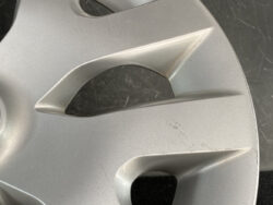 Close-up of a silver alloy wheel with scratches and scuff marks on the rim