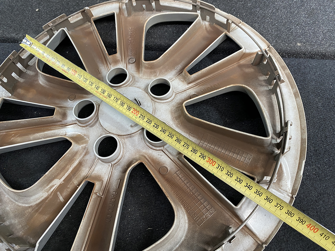 B402_4 TOYOTA PRIUS ZVW50 ZVW51 Genuine 15inch WHEEL CAP / HUB CAP » NZ.95 » JDM-PARTS NZ » JDM-PARTS NZ Brown plastic car wheel hubcap on a dark surface with a yellow measuring tape stretched diagonally across it, showing measurements around 200–400 mm. TOYOTA PRIUS ZVW50 ZVW51 Genuine 15inch WHEEL CAP / HUB CAP » JDM-PARTS NZ