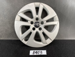 Silver Toyota hubcap with a six-spoke alloy design and central emblem, placed on a dark surface.