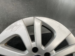 Silver alloy car wheel rim with visible surface scratches and scuffs across the spokes and edge.