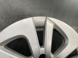 Close-up of a silver alloy car wheel rim with visible surface scratches along the edge near the spoke junction.