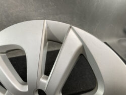 Close-up of a silver alloy car wheel rim with a visible crack along a spoke edge.