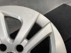 Close-up of a silver alloy car wheel rim with visible curb damage and scratches at the edge of the rim edge pattern.
