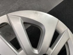Close-up of a silver alloy car wheel rim with visible scratches and scuffs against a dark floor background