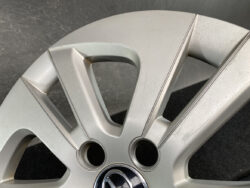 Close-up of a silver alloy car wheel rim showing spoke design, hub area, and lug-nut holes with a center cap visible