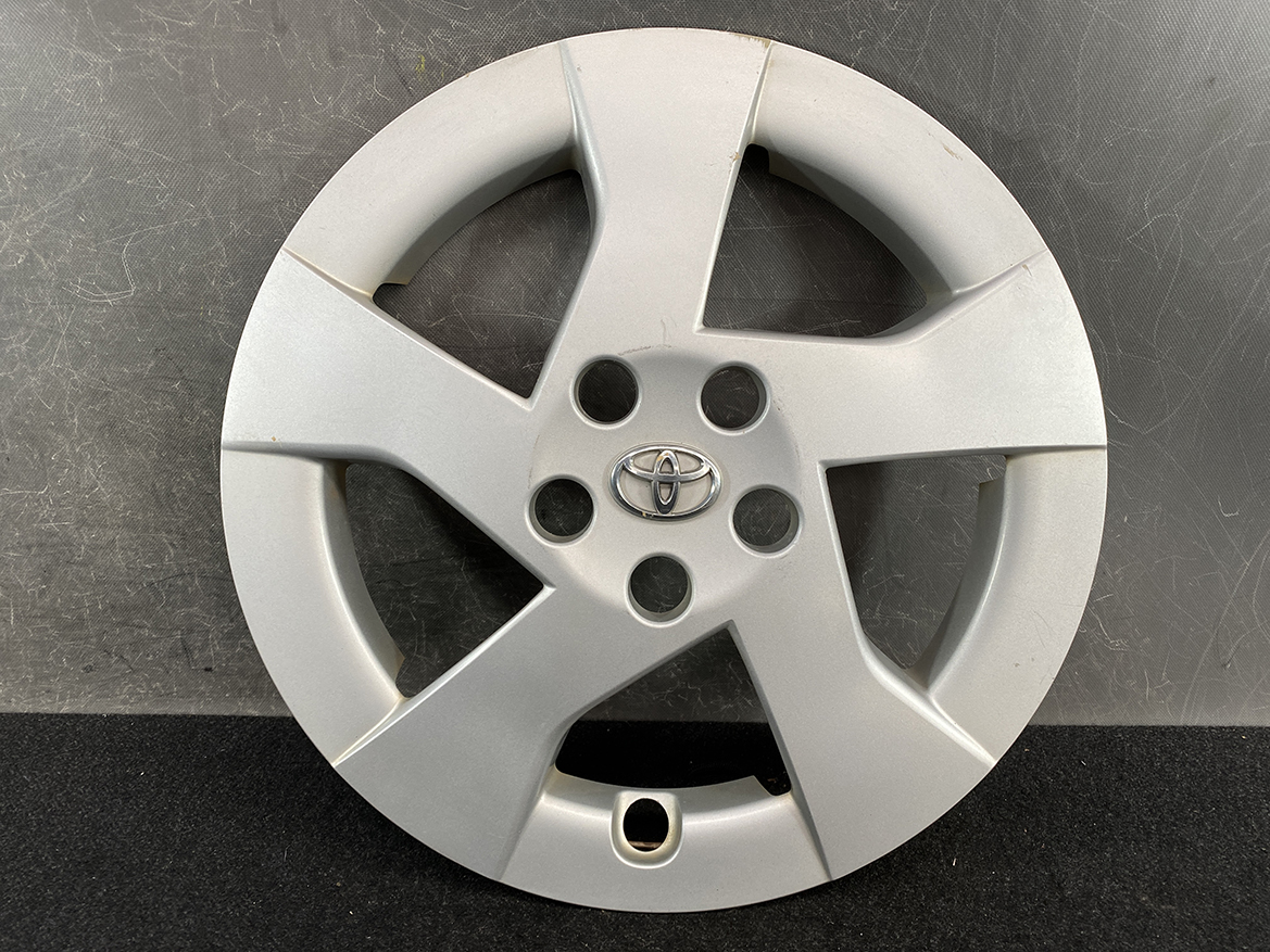 B410_2 TOYOTA PRIUS ZVW30 ZVW35 Genuine 15inch WHEEL CAP / HUB CAP » NZ.95 » JDM-PARTS NZ » JDM-PARTS NZ Silver Toyota alloy wheel cover with five-spoke design and central Toyota emblem on a dark surface. TOYOTA PRIUS ZVW30 ZVW35 Genuine 15inch WHEEL CAP / HUB CAP » JDM-PARTS NZ