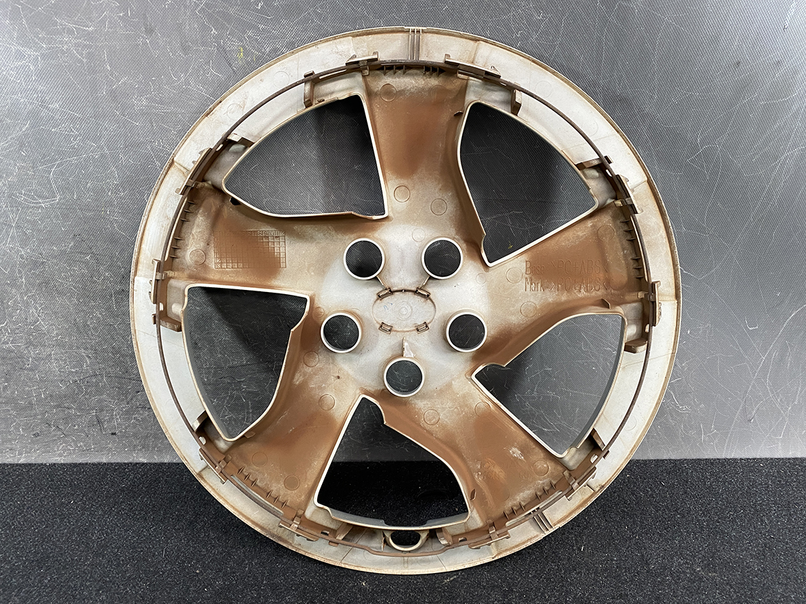 B410_3 TOYOTA PRIUS ZVW30 ZVW35 Genuine 15inch WHEEL CAP / HUB CAP » NZ.95 » JDM-PARTS NZ » JDM-PARTS NZ Rusty metal car wheel rim with five spokes and central lug holes, resting on a dark surface. TOYOTA PRIUS ZVW30 ZVW35 Genuine 15inch WHEEL CAP / HUB CAP » JDM-PARTS NZ