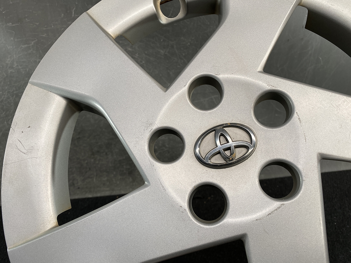 B410_4 TOYOTA PRIUS ZVW30 ZVW35 Genuine 15inch WHEEL CAP / HUB CAP » NZ.95 » JDM-PARTS NZ » JDM-PARTS NZ Close-up of a silver Toyota alloy wheel hubcap featuring the Toyota emblem in the center and circular lug-hole cutouts around it. TOYOTA PRIUS ZVW30 ZVW35 Genuine 15inch WHEEL CAP / HUB CAP » JDM-PARTS NZ