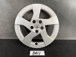 Silver Toyota wheel cover with five spokes and center emblem on a dark surface