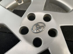 Close-up of a silver Toyota alloy wheel with a central Toyota emblem and five lug nut holes visible around the emblem