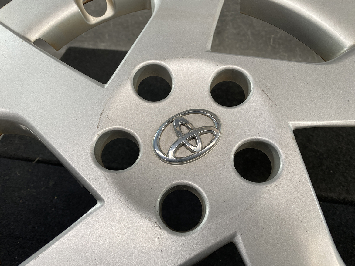 B411_4 TOYOTA PRIUS ZVW30 ZVW35 Genuine 15inch WHEEL CAP / HUB CAP » NZ.95 » JDM-PARTS NZ » JDM-PARTS NZ Close-up of a silver Toyota alloy wheel with a central Toyota emblem and five lug nut holes visible around the emblem TOYOTA PRIUS ZVW30 ZVW35 Genuine 15inch WHEEL CAP / HUB CAP » JDM-PARTS NZ
