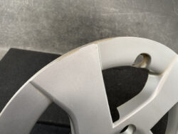 Close-up of a silver plastic wheel cover with a chipped edge along the rim.