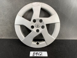 Silver Toyota hubcap with five-spoke design and central emblem on a dark surface, label reads B412 nearby