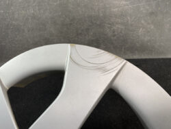 Close-up of a scratched silver alloy wheel spoke with scuff marks along the edge.