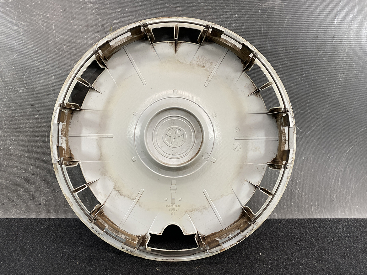 B413_3 TOYOTA VOXY ZWR80 Genuine 15inch WHEEL CAP / HUB CAP 2595 x1 » NZ.95 » JDM-PARTS NZ » JDM-PARTS NZ Round Toyota hubcap with central emblem, dirty and scuffed, resting on a dark surface. TOYOTA VOXY ZWR80 Genuine 15inch WHEEL CAP / HUB CAP 2595 x1 » JDM-PARTS NZ