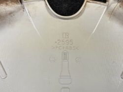 Close-up of a white plastic surface with molded text '2595' and 'PC+ABS' plus a small bottle illustration (material indicator).