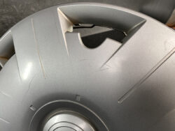 Close-up of a gray circular plastic lid with a broken notch and visible scratches.