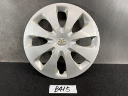 Silver Toyota hubcap with a multi-spoke design and center emblem on a black surface.