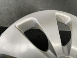 Close-up of a silver alloy wheel with small scratches and scuffs on the rim edge near a hollow spoke opening, photographed indoors.