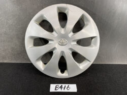 Silver Toyota hubcap with central emblem, photographed against a dark surface.
