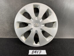 Silver Toyota hubcap with eight teardrop-shaped spokes and center emblem, displayed on a dark surface.