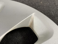 Close-up of a silver car panel with a small crack at a seam near a joint.