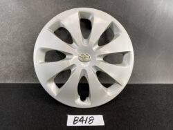 Silver Toyota hubcap with a central Toyota emblem, resting on a dark surface.