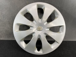 Silver Toyota hubcap with a multi-spoke design and centered Toyota emblem viewed head-on in front of a dark backdrop.