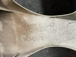Close-up of a Toyota automotive part with stamped part number 42602-52540 and material PC+ABS