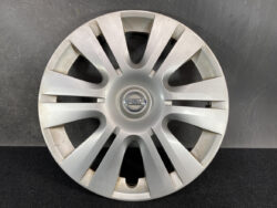 Silver Nissan hubcap with multiple spokes and centered Nissan logo against a dark background, close-up image for a car wheel accessory