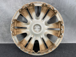 Bronze-toned alloy car wheel rim with ten curved spokes on a dark surface.